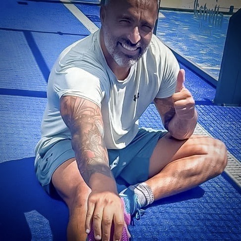 Happy padel player sitting on a dry court after rain and sandstorm, with the court protected by Courtcovers All-Weather Padel Court Covers